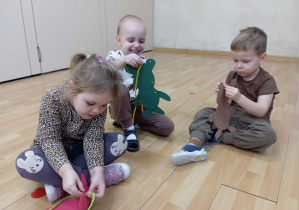 Dzieci przekładją sznurowadło przez sylwetę misia.