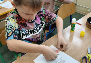 Chłopiec wkleja odznakę do Paszportu Odkrywcy Praw Dziecka.