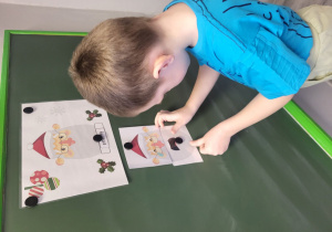 Tymon dobiera i układa obrazek z odpowiednią emocją Mikołaja.