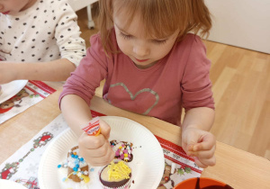 Dziewczynka dekoruje babeczkę.