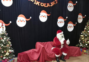 Święty Mikołaj siedzi na kanapie i mówi do mikrofonu