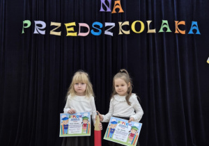 Dziewczynki pozują do zdjęcia z dyplomami