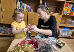 Mama z córką siedzą przy stoliku, robią stroik