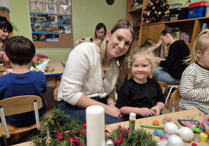 Mama z córką siedzą przy stoliku, robią stroik