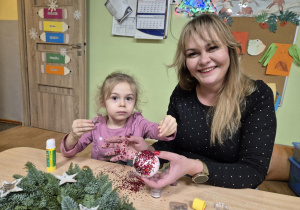Mama z córką siedzą przy stoliku, robią stroik