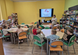 Dzieci siedzą przy stolikach w bibliotece