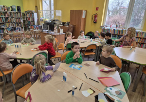 Dzieci siedzą przy stolikach, wykonują pracę plastyczną