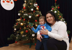 Zdjęcie chłopca z mamą na tle choinki.