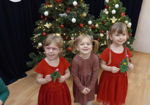 Dziewczynki trzymające w ręku własnorecznie udekorowane choinki.