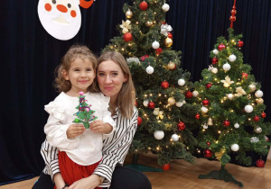 Zdjęcie dziewczynki z mamą na tle choinki.