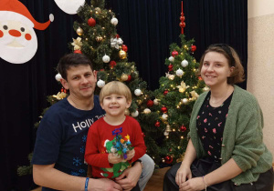 Zdjęcie chłopca z rodzicami na tle choinki.