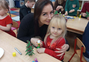 Dziewczynka z mamą dekorują choinkę.