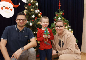 Zdjęcie chłopca z rodzicami na tle choinki.