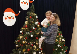 Zdjęcie dziewczynki z mamą na tle choinki.