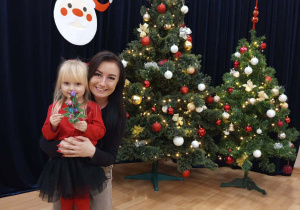 Zdjęcie dziewczynki z mamą na tle choinki.