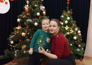 Zdjęcie chłopca z mamą na tle choinki.