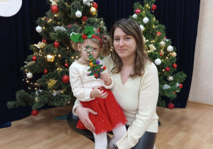 Zdjęcie dziewczynki z mamą na tle choinki.