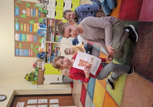 Dzieci siedzą na dywanie.