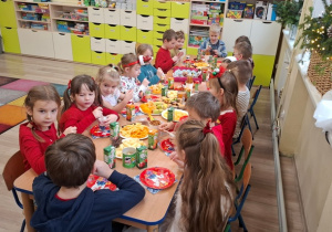 Dzieci siedzą przy stołach.