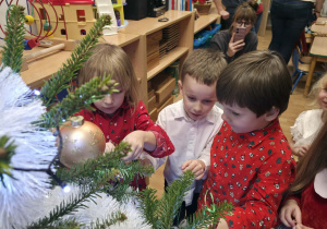 Chłopcy ubierają choinkę.