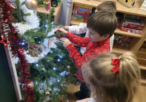 Dzieci ubierają choinkę.