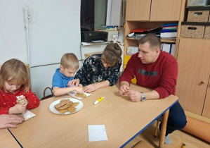 Chłopiec z rodzicami dekorują pierniczki.