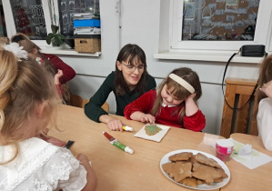 Dziewczynka z mamą ozdabia pierniczki.