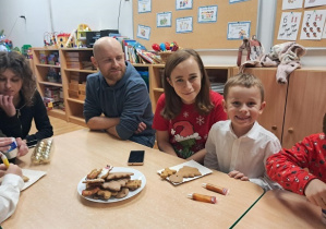 Chłopiec z rodzicami dekoruje pierniczki.