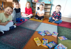 dzieci siedzą na dywanie przy różnego rodzaju popcornie