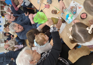 dzieci wraz z dziadkami siedzą przy stole