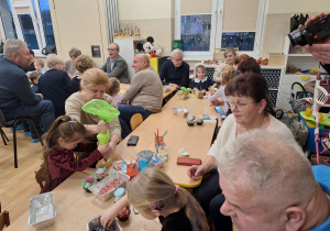 dzieci z dziadkami siedzą przy stole