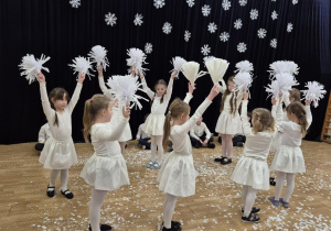 Dziewczynki w białych strojach tańczą taniec śnieżynek