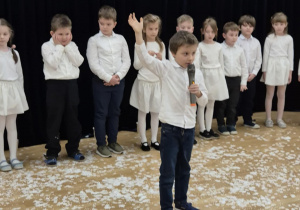 Chłopiec z mikrofonem w ręku recytuje wiersz