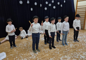 Chłopcy w białych koszulach i czarnych kapeluszach śpiewają piosenkę