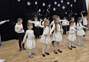 Dzieci rozsypują papierowe śnieżynki