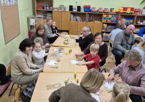 Dzieci wspólnie z dziadkami pracują przy stolikach