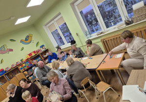 Dzieci wspólnie z dziadkami pracują przy stolikach