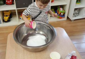 Chłopiec wsypuje sól do miski.