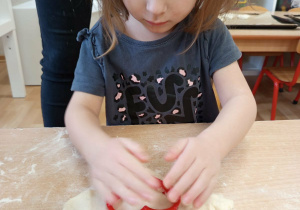 Dziewczynka odbija foremkę w kształcie serca z masy solnej.