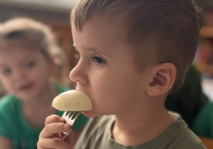Chłopczyk zjada jajko nadziane na widelec.
