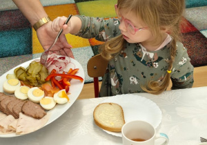 Dziewczynka wybiera z talerza warzywa.