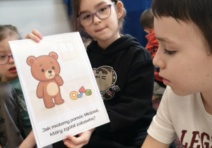 Dziewczynka omawia swój sposób na pomoc misiowi.