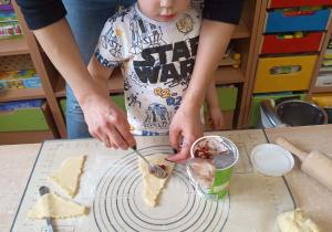 Chłopiec smaruje ciasto marmoladą.