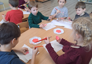 Dzieci malują farbami plastikowe butelki.