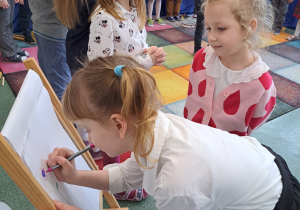 Dzieci rysują kwiatki w laurce dla dziadków.