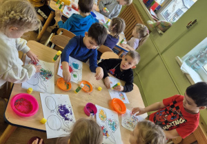 Dzieci wyklejają kolorowym ryżem obrazki