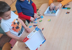 Chłopcy układają puzzle.
