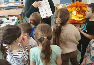 Dzieci słuchają, w jaki sposób rozwiązać kartę pracy.