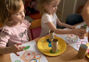 Dzieci wykonują pracę plastyczną przy stoliku