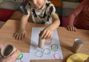 Marcel wykonuje pracę plastyczną przy stoliku